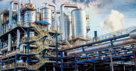Planta de procesamiento industrial con tanques, tuberías y estructuras metálicas